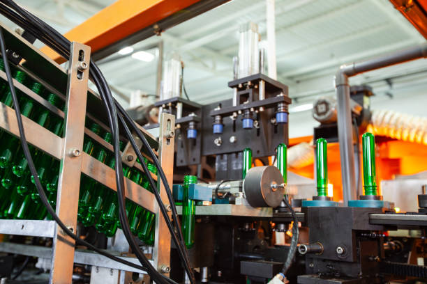 istock Machine assembling green glass bottles in a factory during daylight hours 2195018045