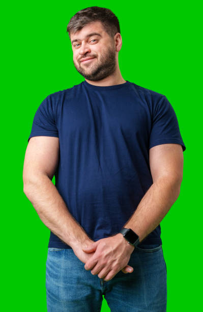 istock Man standing with a thoughtful expression in a casual outfit against a green background 2195018234