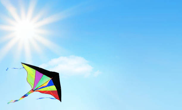 Multi colored kite flying in the blue sky with beautiful sunbeams. Space for copy.
