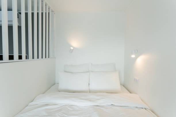 istock A cozy bed in a small room, adorned with white sheets and pillows 2195025145