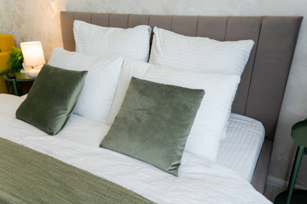 istock A hotel room has a bed with crisp white sheets and green pillows 2195025161