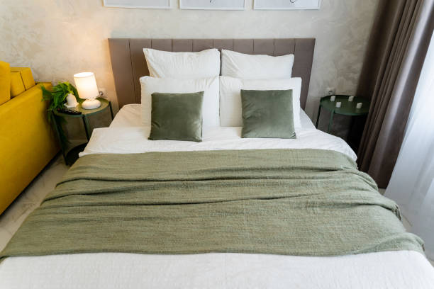istock A bed with white sheets and green pillows in a yellow couch room 2195025165