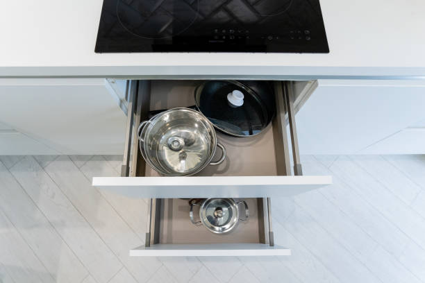 istock A kitchen drawer that is filled with various pots and pans beneath a stove 2195025187