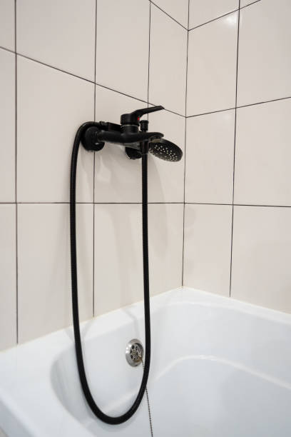 istock In a beautifully designed bathroom, there is a white bathtub that features a sleek black shower head, which is elegantly attached to the wall, creating a stylish look in the space 2195025266