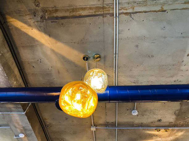 There is a ceiling that features a blue pipe prominently alongside it, with two stylish lights elegantly hanging down from it, contributing to the overall ambiance of the room