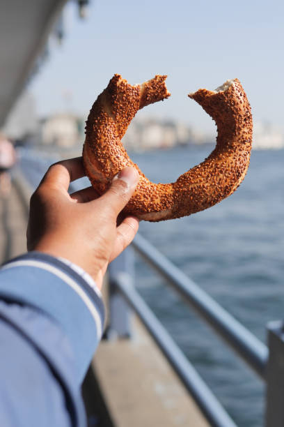 man holding a Turkish Bagel Simit against istanbul city background .