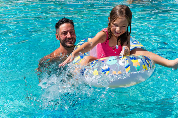 istock Father and daughter having fun in swimming pool on summer vacation 2195029057