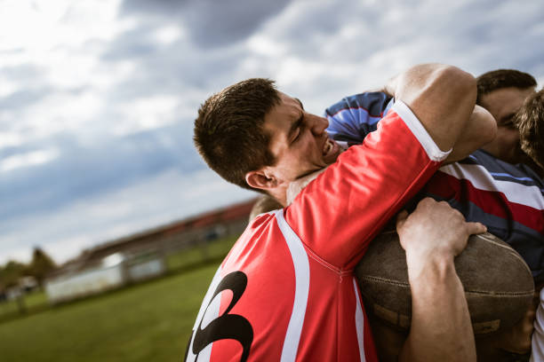 Determined player making an effort while trying to get through defensive players on a rugby match at playing field.