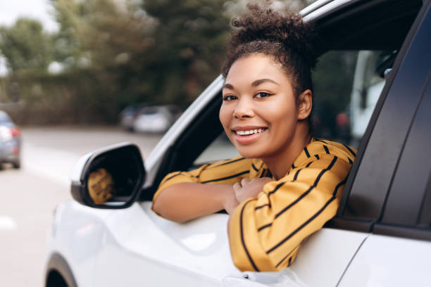 istock Smiling pretty African woman sitting at her car while looking at open window 2195040828