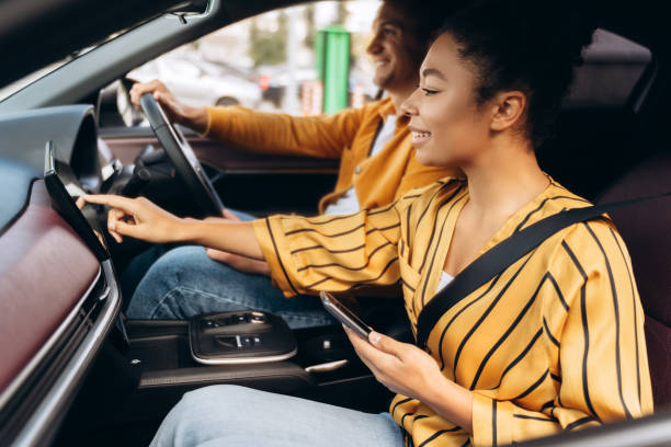 istock African American woman using display and smartphone while traveling with man by car 2195040848