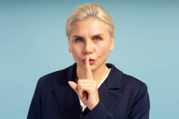 istock Businesswoman making silence gesture on blue background 2195041156