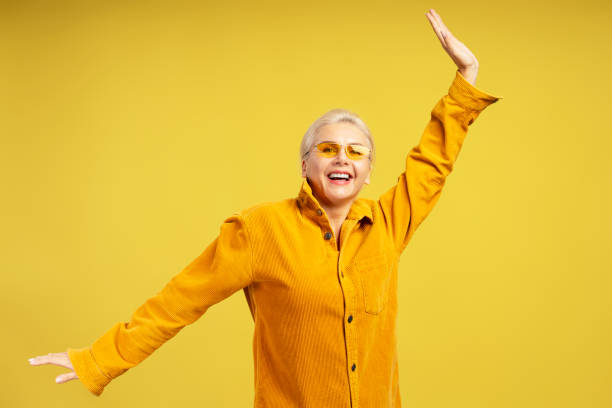 istock Happy middle aged woman dancing and having fun on yellow background 2195041163