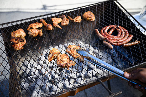 Meat skewers, chicken wings, and bread on outdoor barbecue grills