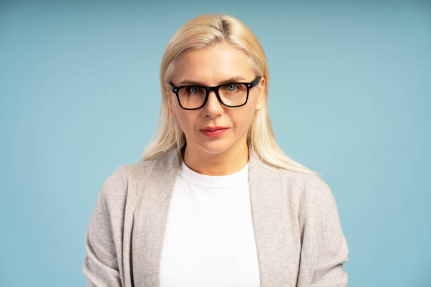 istock Serious blond woman wearing glasses posing on blue background 2195041213