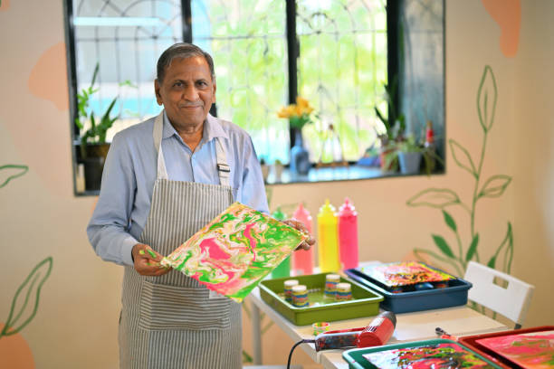 istock Senior man proudly displaying his Fluid Art Creation at an Art workshop 2195041632