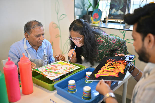 istock Artisan guiding senior man in fluid art straw technique during an art workshop 2195041643