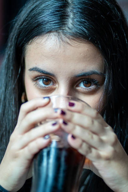 Young woman drinking refreshing soda from glass in restaurant