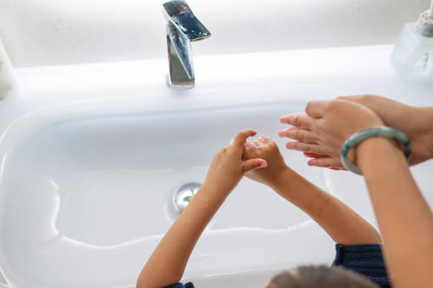 A child’s hands are covered in foam from soap while looking in a mirror, highlighting important lessons in hygiene taught in a fun and engaging way.