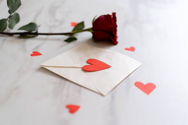 istock Romantic letter with a rose and heart confetti on a marble table ready for a special occasion. 2195048962