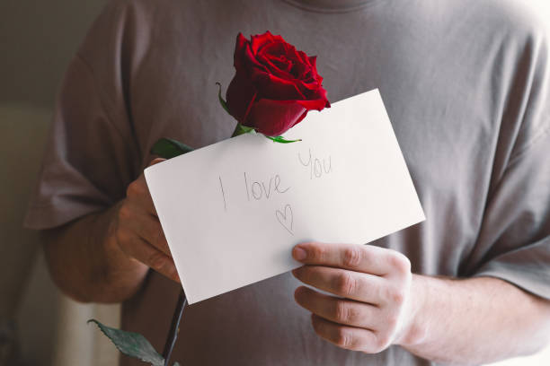 istock Man holding a red rose and a handwritten note expressing love. 2195049159