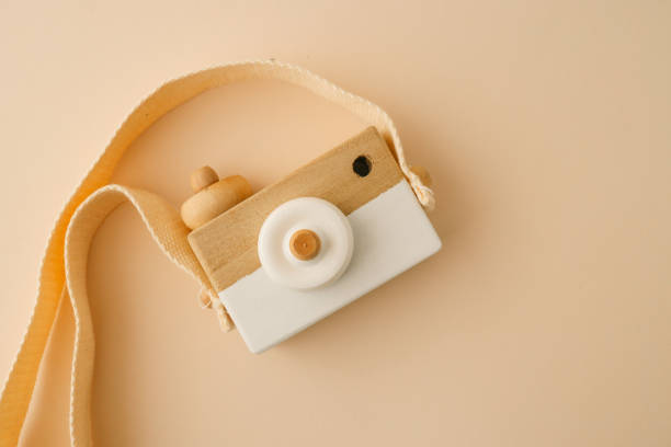 istock Wooden toy camera with a beige strap on a minimalistic light beige background, showcasing simplicity, eco-friendliness, and creative play 2195049185