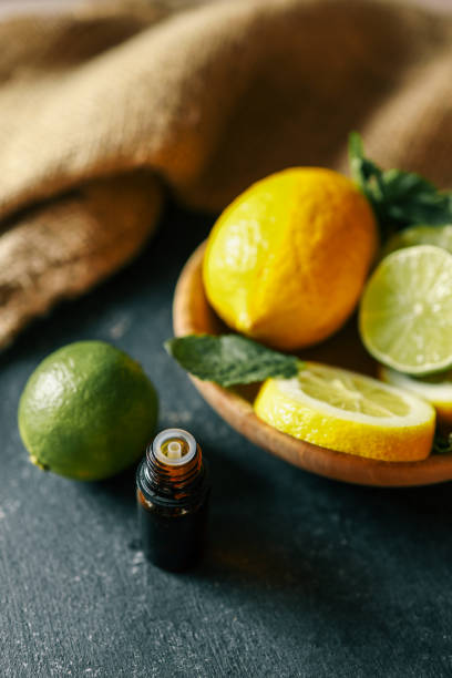 istock A dark amber essential oil bottle placed on a rustic dark surface with fresh lemons, limes, and mint leaves in the background. A natural and aromatic scene perfect for wellness and organic themes 2195049508
