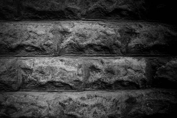 A close-up view of a rugged stone wall showcases its unique textures and patterns. The monochrome effect emphasizes the depth and detail of each stone.