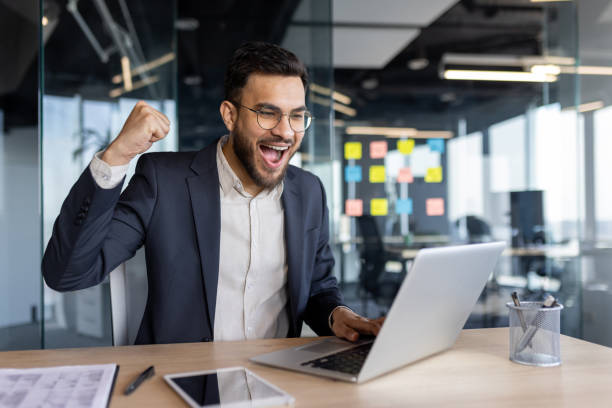 istock Mature businessman celebrating success while using a laptop in a modern office 2195050150