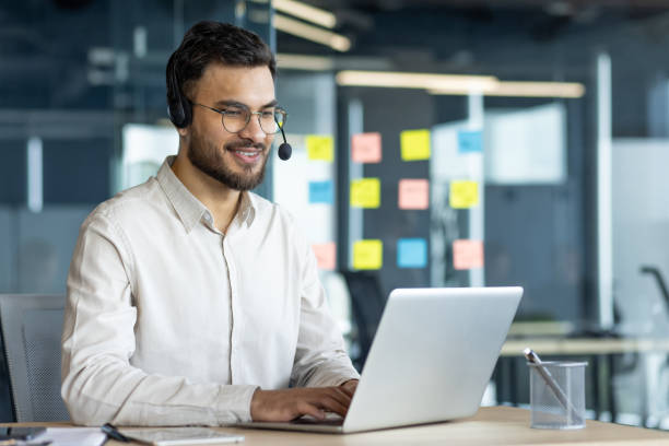 istock Latin American businessman using laptop with headset in modern office 2195050210