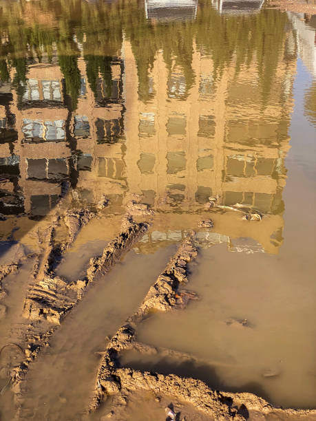 High angle view of the reflection of a residential building next to tire track over flooded ground after heavy rain in the city of Valencia, Spain