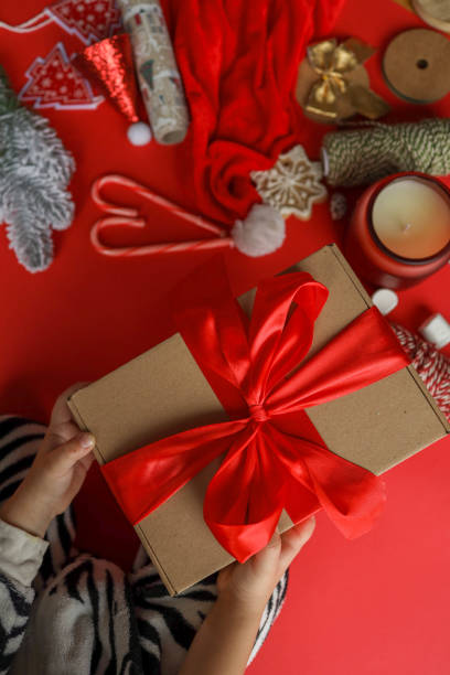 istock Child holding gift with bow, cozy christmas 2195051305