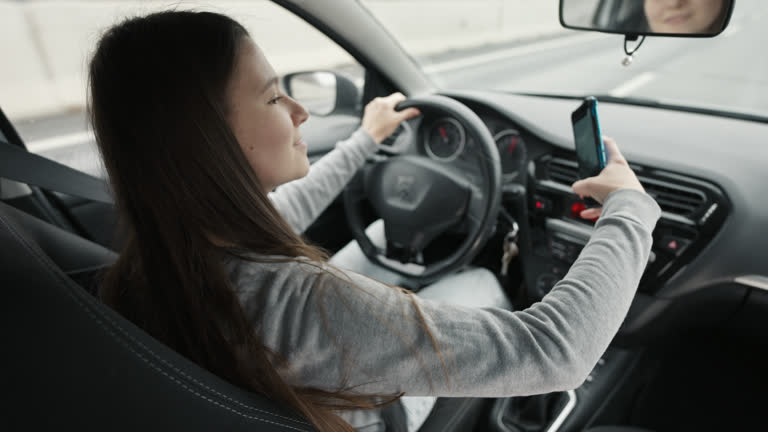 Rear View of Irresponsible Young Woman Taking Selfie With Mobile Phone While Driving Car