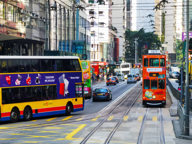 HongKong, China - January 21, 2025 : A bustling city street scene, viewed from a street level perspective.  Double-decker buses, trams, cars, and pedestrians fill the road and sidewalks. Buildings line the street.
