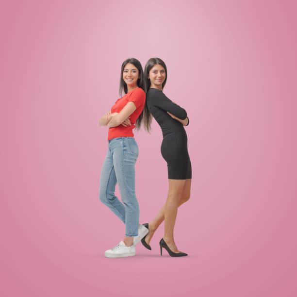 Smiling twins posing back to back with different outfits: young student and successful businesswoman