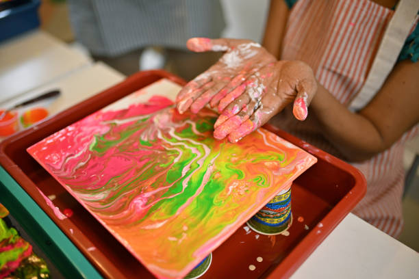 Close-up of hands with vibrant paints during a fluid art session, capturing the dynamic moment and colorful patterns in an engaging workshop atmosphere