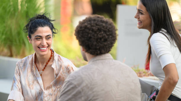 istock Three young adults having a conversation and smiling together outdoors 2195075843