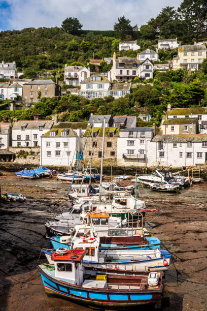 Fishing boats grounded at low tide in Polperro harbour, with traditional houses rising on the hillside.