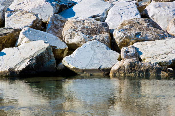 istock Stone breakwater rocks are reflected in the water 2195080113
