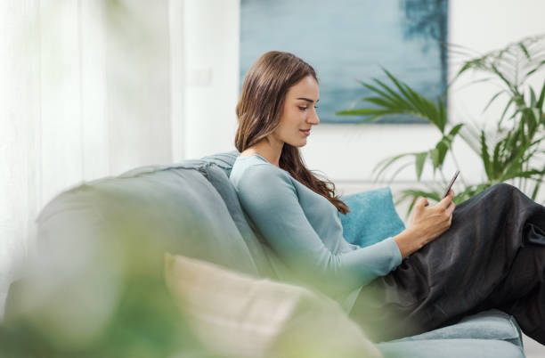istock Beautiful young woman relaxing at home and using her smartphone 2195082979