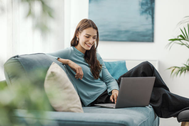 istock Young woman relaxing on the couch and using a laptop 2195084429
