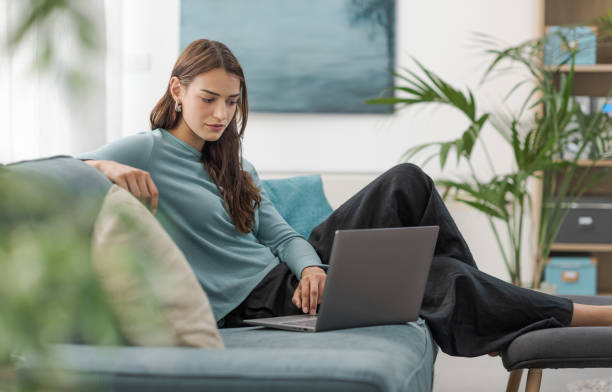 istock Young woman relaxing on the couch and using a laptop 2195085439
