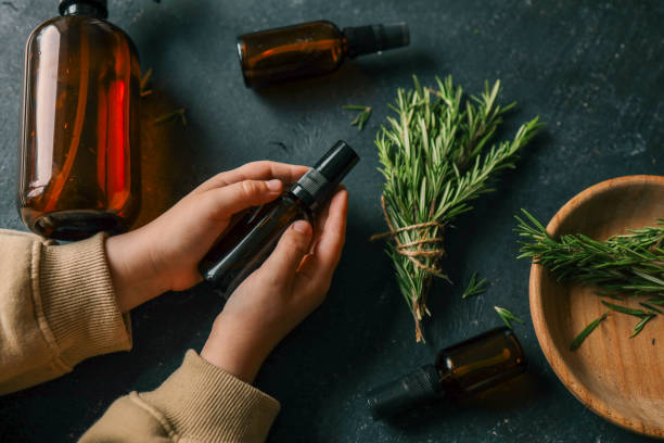 istock Amber glass spray bottle with a black cap placed on a dark rustic surface, surrounded by rosemary sprigs and natural decor elements. Concept of natural, eco-friendly cosmetics or aromatherapy products 2195086123