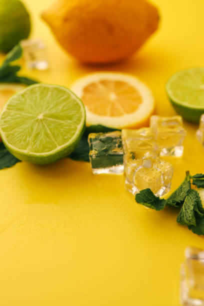 istock Fresh lemons, limes, mint leaves, and ice cubes arranged on a vibrant yellow background. A refreshing and colorful composition perfect for summer themes and beverage presentations 2195086528