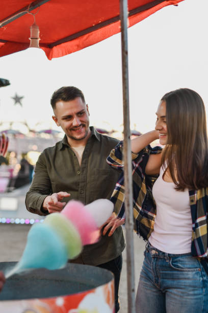 istock Joyful Couple Waiting for Their Cotton Candy At Amusement Park 2195086554
