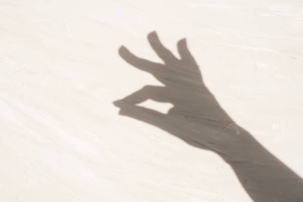 istock shadow of a hand with two fingers clasped on a light textured surface. elegance, dance. copy space 2195089782