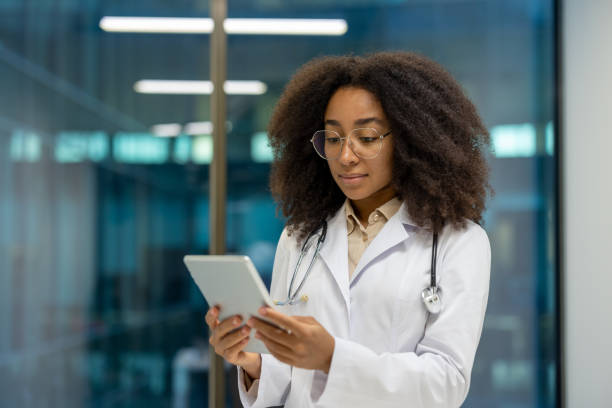 istock Serious female doctor focused and thinking using tablet computer, female doctor in white medical coat working inside clinic office 2195090091