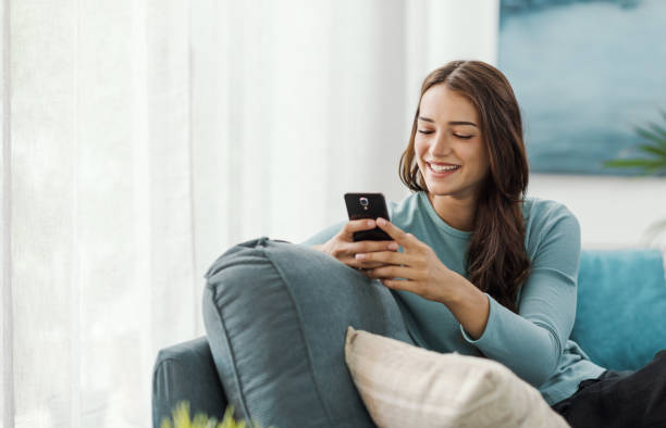 istock Beautiful young woman relaxing at home and using her smartphone 2195091214