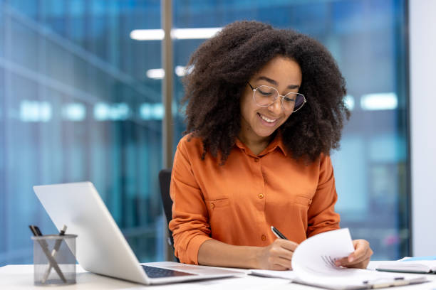 istock Professional woman working in modern office reviewing documents with laptop 2195091553