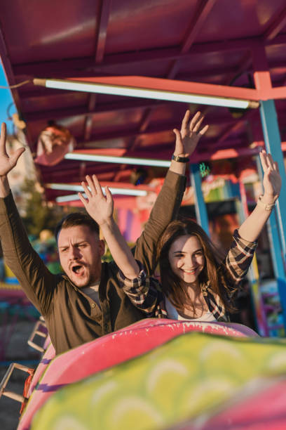 istock Happy Looking Friends Raising Arms While Enjoying Speedy Rollercoaster Ride 2195092349
