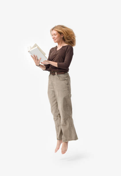 istock Happy young woman reading a book and jumping 2195096036